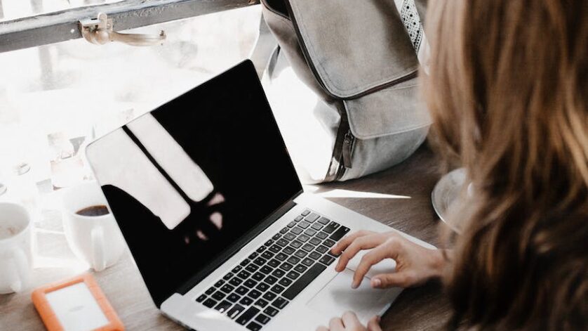 close up photography of woman sitting beside table while using macbook