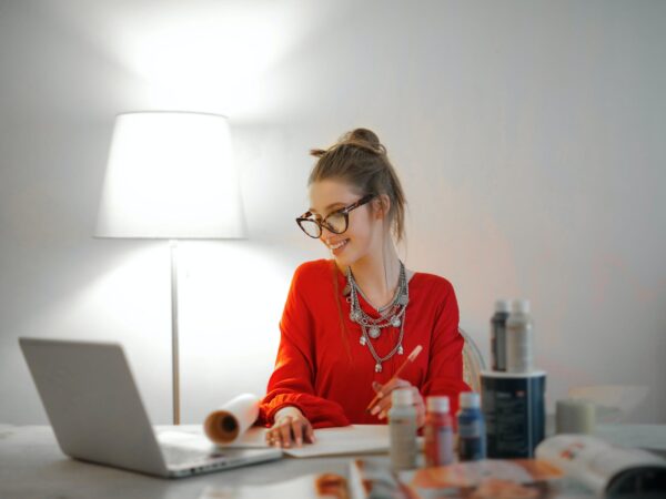 woman in red long sleeve shirt looking at her laptop